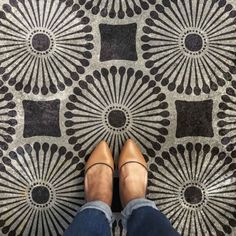 the feet of a person standing on a patterned floor