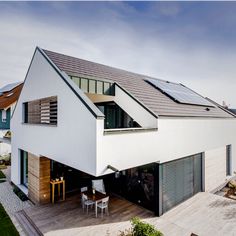 a modern house with solar panels on the roof and an open patio area in front