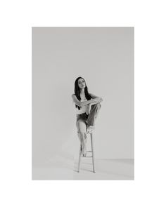 a black and white photo of a woman sitting on a stool