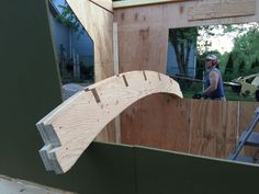 a man standing in front of a wooden structure with a sawhorse on it's side