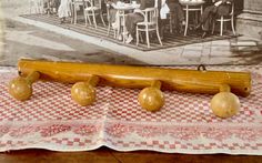 an old fashioned baseball bat and five wooden balls on a checkered tablecloth next to a photo