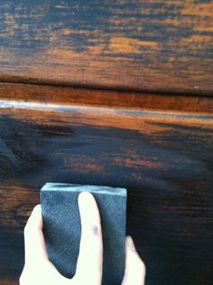 a person's hand on top of a piece of black cloth next to a wooden table