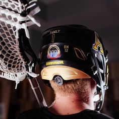 a close up of a person wearing a helmet and holding a lacrosse stick in his hand