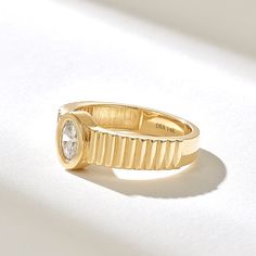 a yellow gold ring with a diamond in the center on a white surface, close up