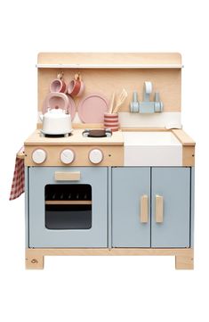 a wooden play kitchen with blue cabinets and pink accessories on the top shelf, including a pot and pan