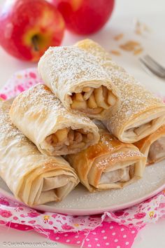 apple turnovers on a plate with powdered sugar and an apple in the background