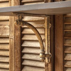 an old wooden shelf with metal brackets on the top and bottom, in front of shutters