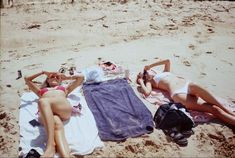 two women laying on the beach with towels