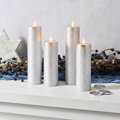 three white candles sitting on top of a table next to some blue and gold decorations