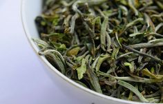 a white bowl filled with green tea leaves