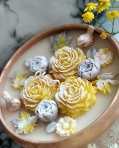 some yellow and white flowers in a bowl on a marble counter top with gold accents