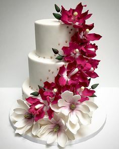 a three tiered white cake with pink flowers on top