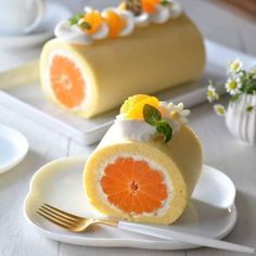 two slices of cake with oranges and whipped cream on top, sitting on plates