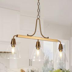 a kitchen light with three lights hanging from it's center and two clear glass shades on the bottom