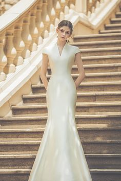 a woman in a wedding dress standing on some steps with her hands on her hips