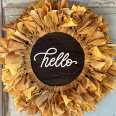 a wreath with the word hello painted on it in white letters and yellow ruffles