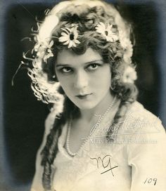 an old black and white photo of a woman with flowers in her hair