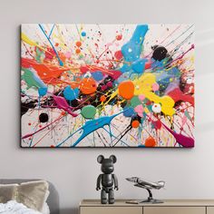 an abstract painting hangs on the wall above a dresser with a teddy bear next to it