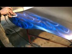 a man working on a car with blue flames