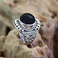 A sterling rope surrounds a polished black onyx in its argent embrace. Bali's legendary silver granules form a halo. Graceful and feminine this ring comes from Balinese designer Komang Wijayana. .925 Sterling silver Adjustable Silver Onyx Ring, Silver Onyx Rings With Black Enamel, Unique Black Sterling Silver Rings, Spiritual Oval Onyx Jewelry, Black Sterling Silver Cabochon Ring, Black Cabochon Sterling Silver Ring, Silver Onyx Cabochon Rings, Black Oval Spiritual Rings, Unique Black Rings With Polished Finish