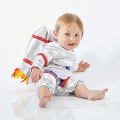 a baby dressed in silver and red sitting on the floor