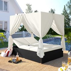 a white canopy bed sitting on top of a wooden deck next to a swimming pool