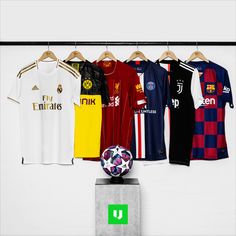 several soccer jerseys are hanging on the wall and there is a ball in front of them