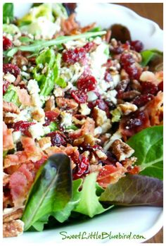 a salad with bacon, lettuce and cranberries in it on a white plate