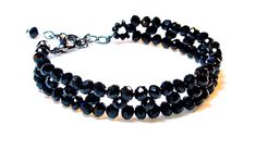 This uniquely designed bracelet is hand-beaded with gorgeous, shimmering Black AB 4mm crystals. It is finished with a gunmetal lobster clasp, and an extender chain for a perfect, adjustable fit. Fits Bracelet Sizes 6 ½ - 7 ½ (approximate). Standard woman's bracelet size is 7. Makes a perfect gift for any special occasion. Treat yourself or someone you love. *Please note the size of the beads in photo 2. All of my items are handmade with care and extra attention to detail and quality. FREE SHIPPI Cheap Black Beaded Crystal Bracelet, Luxury Black Elegant Beaded Bracelets, Cheap Themed Black Bracelets, Black Crystal Bracelet With Faceted Beads, Black Crystal Bracelet With Faceted Beads For Party, Black Faceted Beads Crystal Bracelet For Party, Handmade Black Crystal Bracelet, Black Crystal Bracelet With Spacer Beads, Black Crystal Bracelet With Spacer And Round Beads