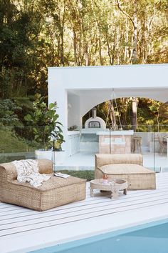 two wicker chairs sitting next to a pool