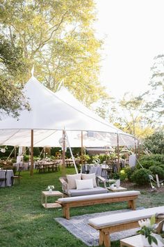 an outdoor seating area is set up with tables and chairs under a large white tent