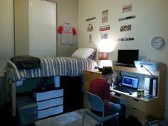 a person sitting at a desk in front of a bed with a computer on it