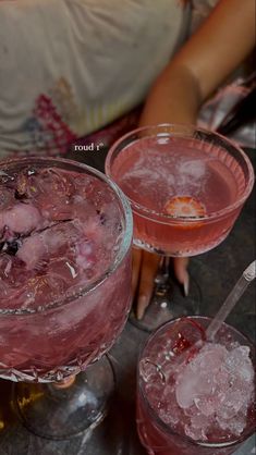 two glasses filled with pink liquid sitting on top of a table next to each other