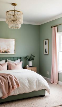 a bedroom with green walls and white bedding, chandelier above the bed