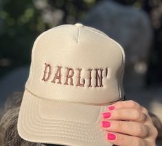 Add a touch of Southern sweetness to your style with our embroidered hat featuring the word 'DARLIN'  embroidered with a western script.  This classic sand-beige colored trucker cap is perfect for anyone who loves Southern charm and effortless style with colors ready for fall! Whether you're heading to a music festival, a day out with friends, or simply want to express your playful side, this hat is a must-have accessory. Details: Colors Available: Sand (Beige), Black, Gray Material: Polyester Foam Front truck cap with Mesh Back adjustable straps Size: One size fits most (adjustable strap) Embroidery: machine embroidered by me using high quality thread   Style: Otto foam trucker cap with a splash of western charm.     Pricing:$25 Shipping:$2 *Processing Time: 1 -2days *Shipping Time: 3-5 b Trendy Snapback Hat For Country Events, Trendy Baseball Cap For Country Events, Trendy Cap For Western-themed Events, Snapback Hats For Country Events In Spring, Trendy Trucker Hat For Spring Country Events, Spring Snapback Hats For Country Events, Spring Western Trucker Hat, Western Style Adjustable Baseball Cap For Country Events, Trendy Adjustable Baseball Cap For Country Events