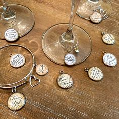 several wine glasses with personalized charms on them sitting on a wooden table next to each other