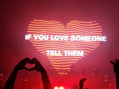 someone is holding their hands up in front of a heart with the words if you love someone tell them