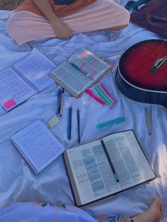 a person laying on a bed with an open book and notebooks next to them