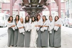 a group of women standing next to each other in front of a train station with fur stolers