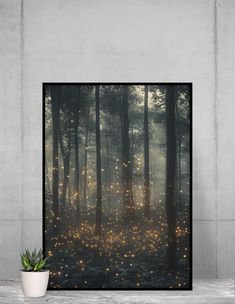 a poster with lights in the forest on it's side and a potted plant next to it