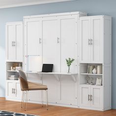 a room with white cabinets and a chair next to a laptop on a desk in front of it