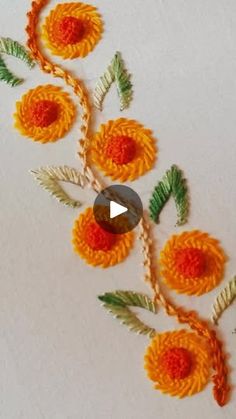 an orange flower with green leaves is on the white surface and there is a video about how to make it