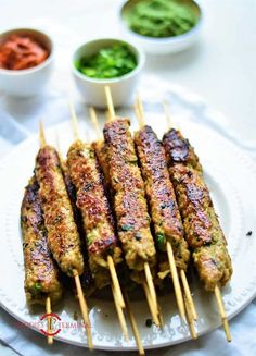 several skewers of food sitting on a plate with dipping sauces around them