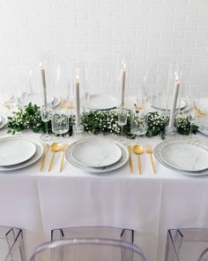 the table is set with plates, silverware and greenery for an elegant dinner