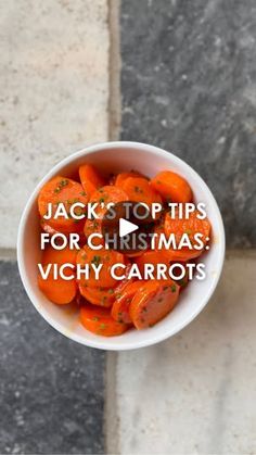 a white bowl filled with carrots sitting on top of a marble floor next to a wall