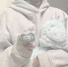 a person wearing a hoodie holding a stuffed animal with a pacifier in their hand