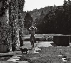 a woman walking down a path next to a dog on top of a grass covered field