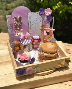 a wooden box filled with food on top of a table next to a sign that says mom