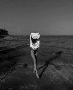 a woman standing on top of a beach next to the ocean