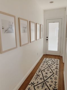 a hallway with pictures on the wall and a rug in front of the door is shown